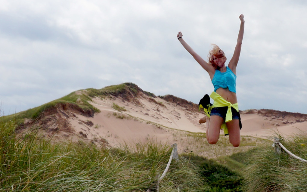 Lindsay jumping in front of the Greenwich Dunes on Prince Edward Island :: I've Been Bit! Travel Blog
