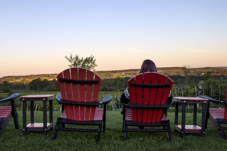 Lindsay enjoying the sunrise at Coffin Ridge Winery The Resting Place Overlooking Vineyards from Red Chairs :: I've Been Bit! A Travel Blog 