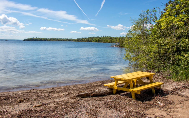 Beach with Yellow Picnic Bench In Front of the Turquoise Water of Lake Huron :: I've Been Bit! Travel Blog