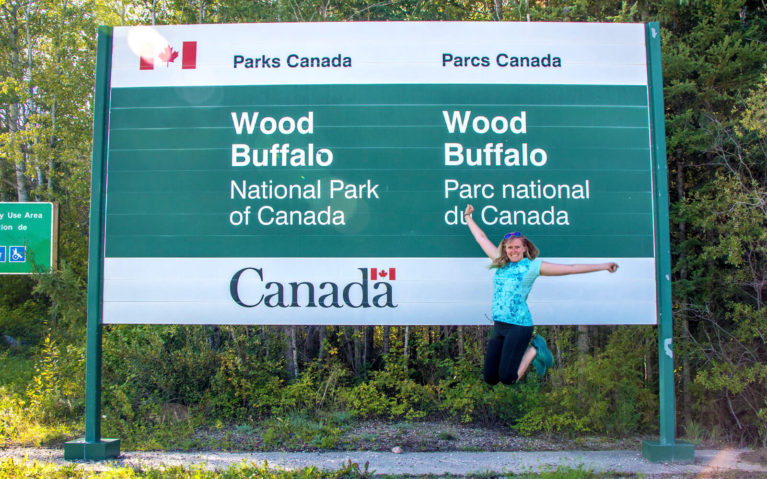 Lindsay Mid-Jump in Front of the Wood Buffalo National Park Sign :: I've Been Bit! Travel Blog