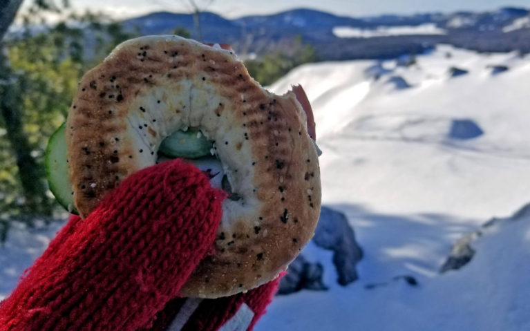 Mitten Holding Bagel Sandwich with Snowy Scene in the Distance :: I've Been Bit! Travel Blog