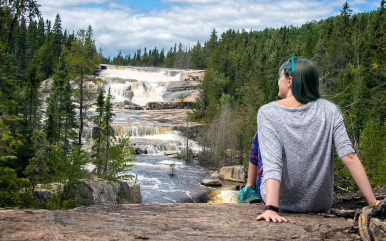 Lindsay Sitting on Ledge with Waterfall in the Distance :: I've Been Bit! Travel Blog