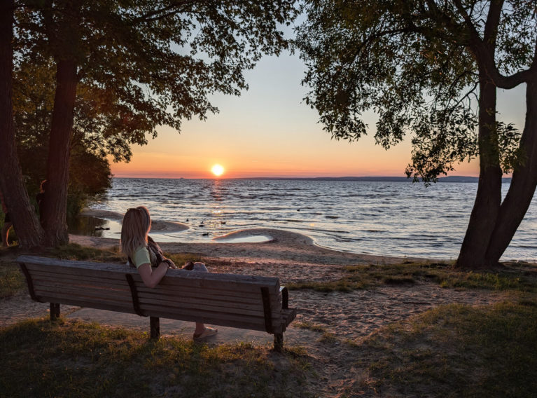 Lindsay Sitting on Bench as the Sun Sets on North Bay's Sunset Beach :: I've Been Bit! Travel Blog